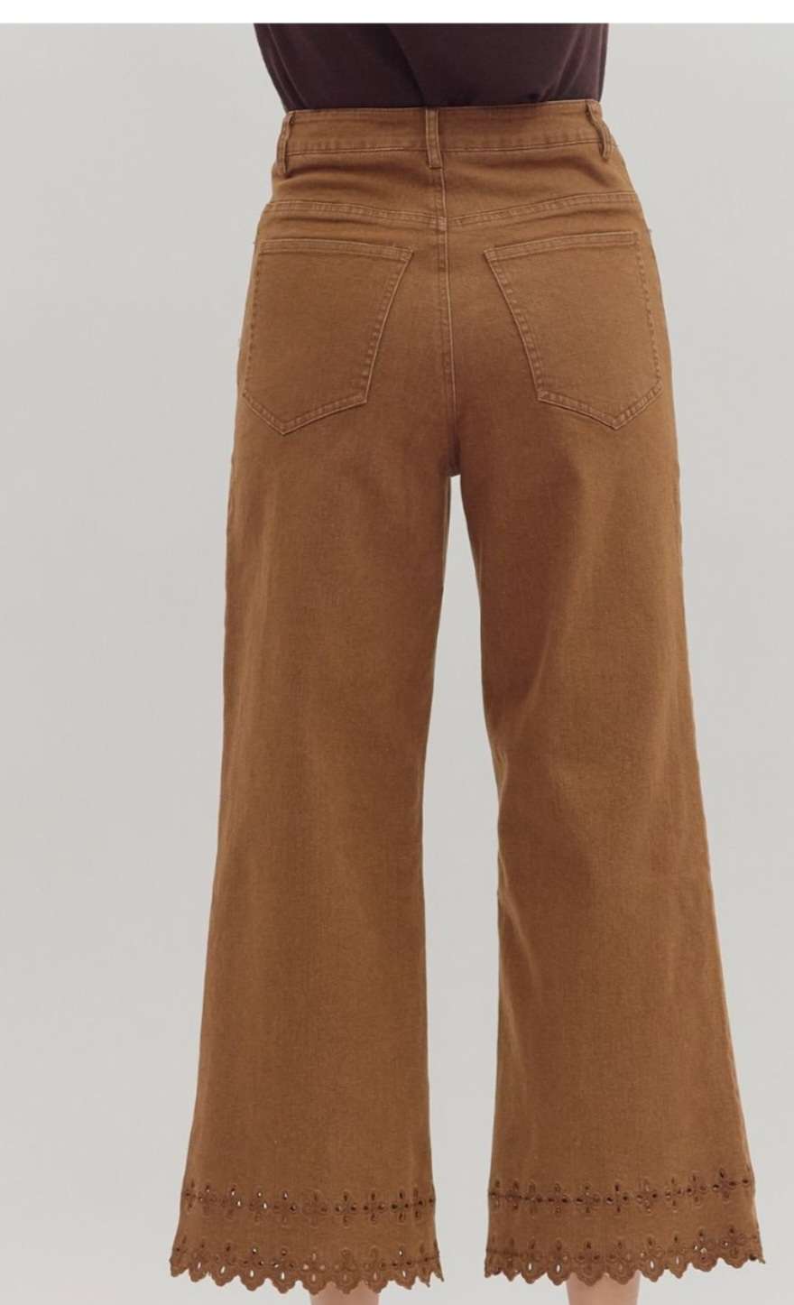 High-waisted brown denim pants featuring decorative eyelet hem