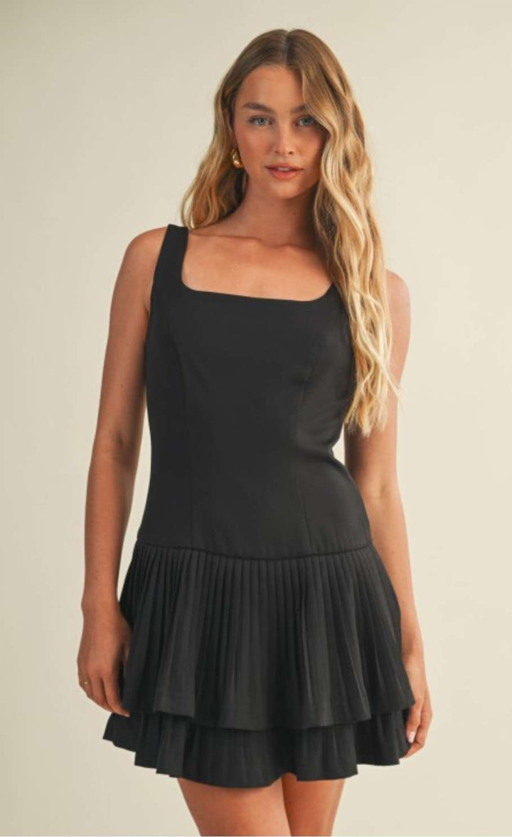 Chic black pleated dress with layered detailing styled for an evening look