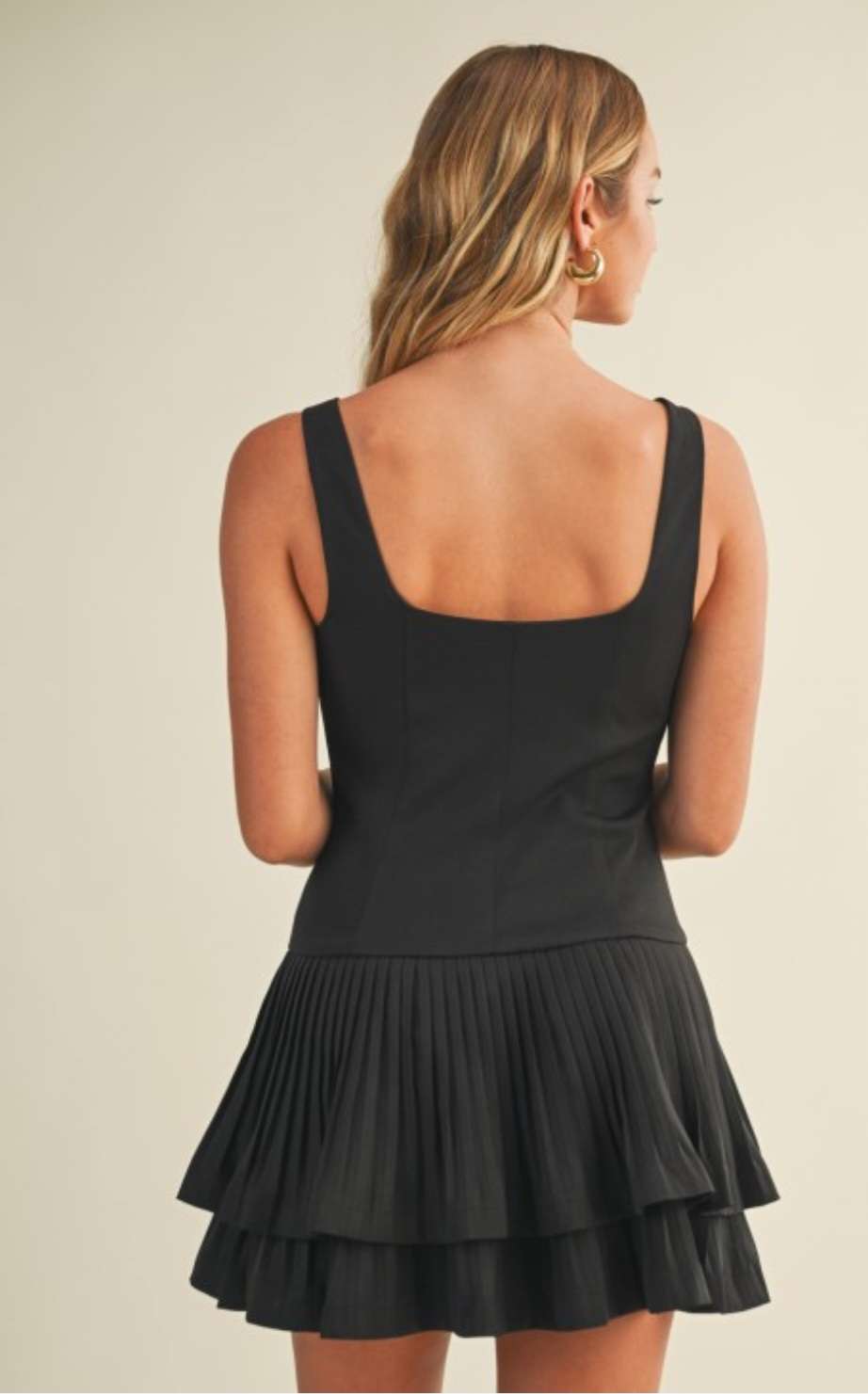 Chic black pleated dress with layered detailing styled for an evening look