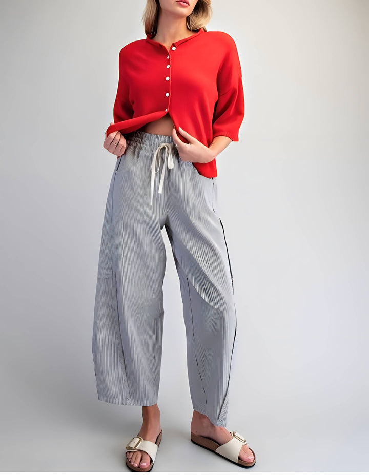 Person wearing a red shirt and light gray pants on a plain background