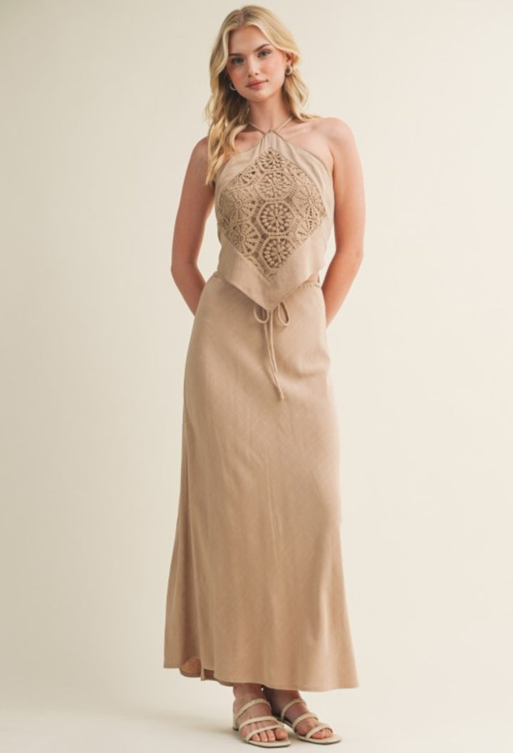 Woman wearing a beige dress with lace detailing on a plain background
