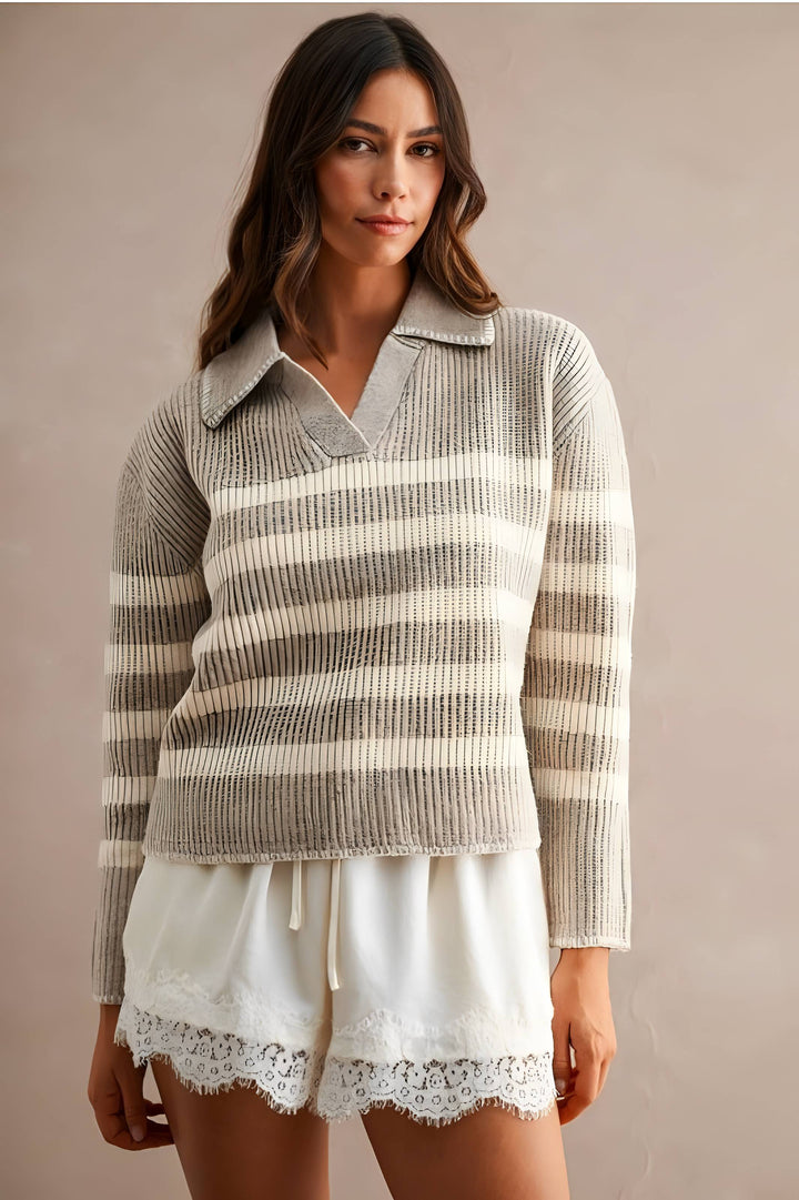 A woman wearing a ribbed knit polo-style sweater with horizontal beige and off-white stripes, paired with white shorts featuring a lace hem, against a plain beige studio background.