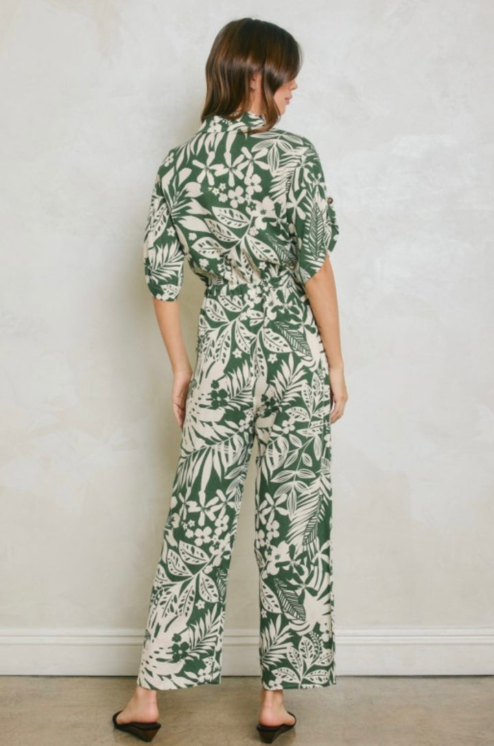 Person wearing a green and white floral jumpsuit against a plain background