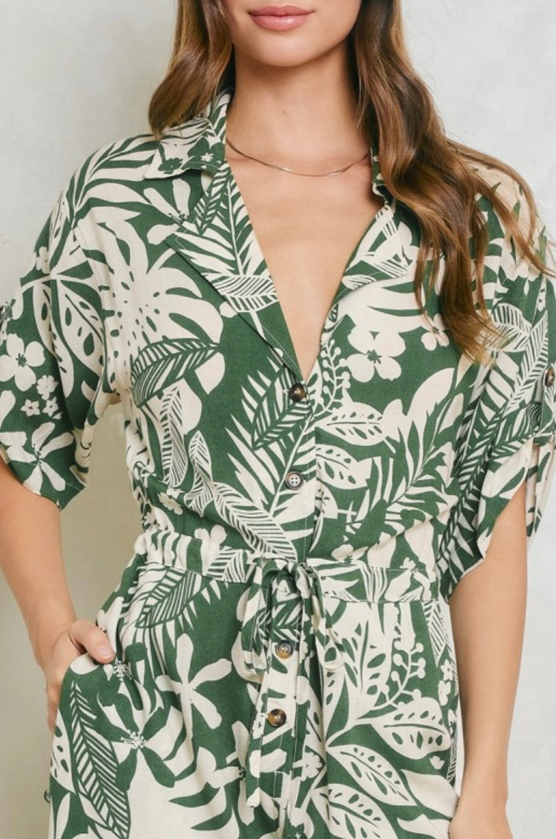 Woman wearing a green and white leaf-patterned dress against a neutral background