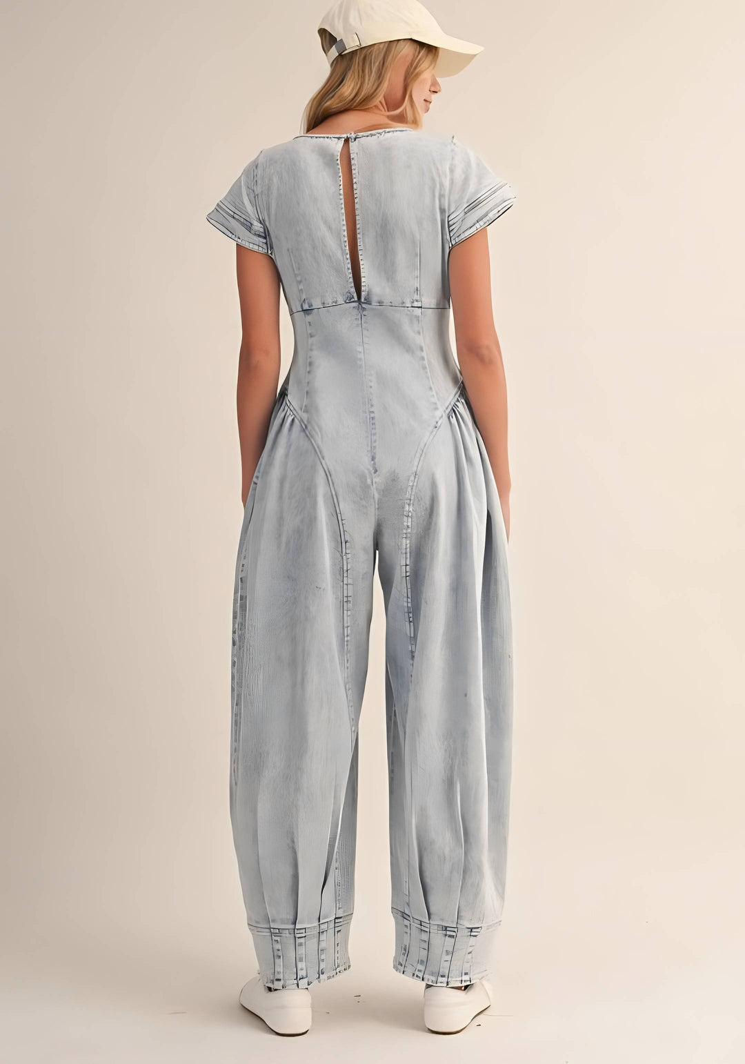 Woman wearing a light blue denim jumpsuit on a beige background