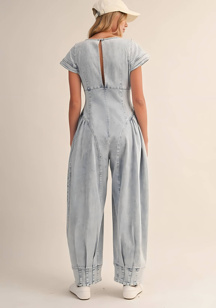 Woman wearing a light blue denim jumpsuit on a beige background