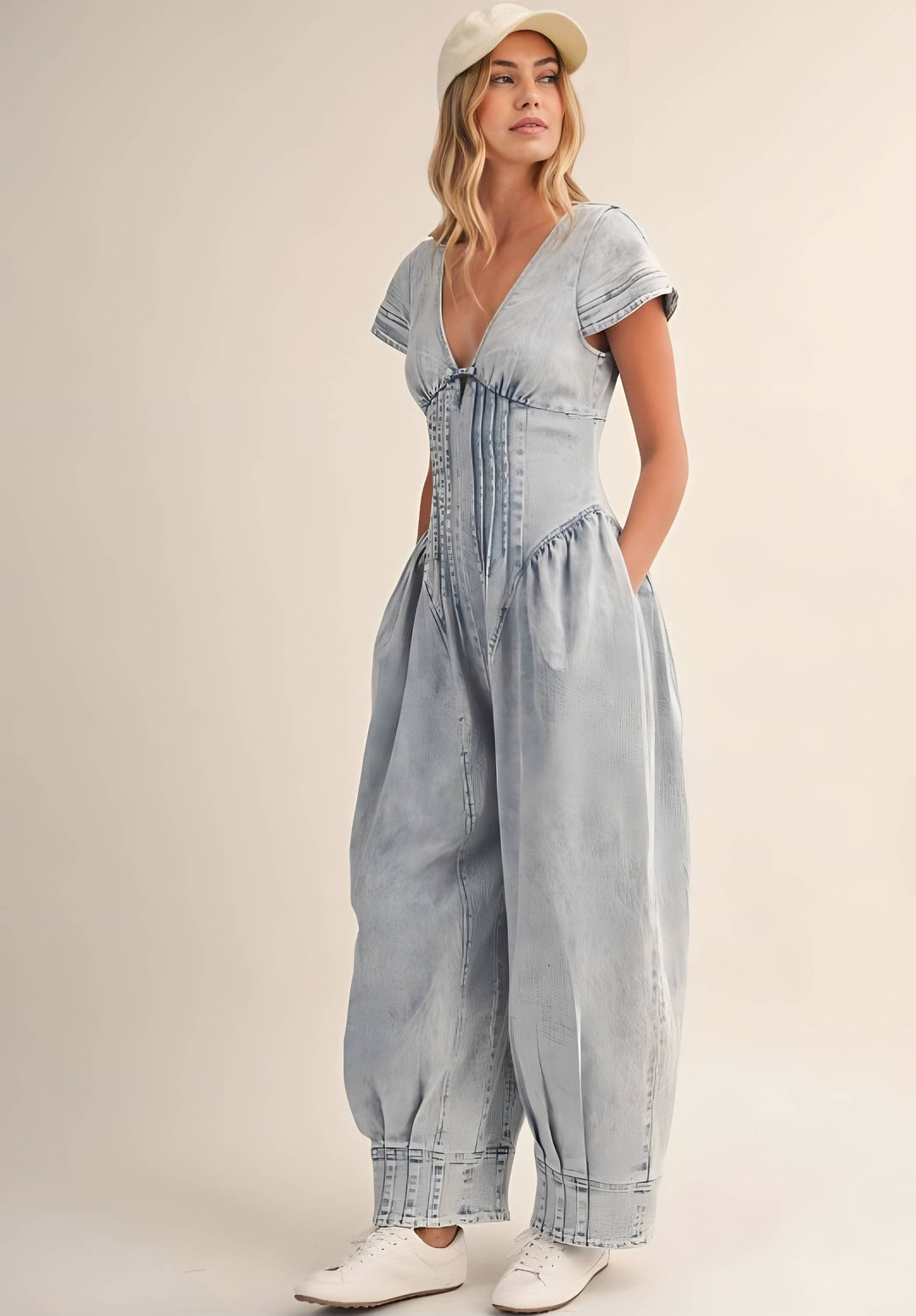 Woman wearing a light blue denim jumpsuit on a beige background