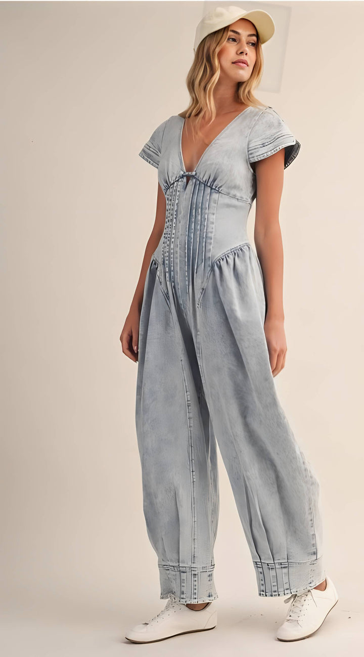 Woman wearing a light blue denim jumpsuit on a beige background