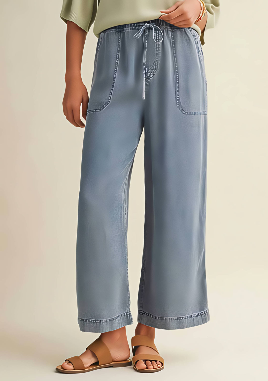 Person wearing light blue wide-leg jeans on a beige background