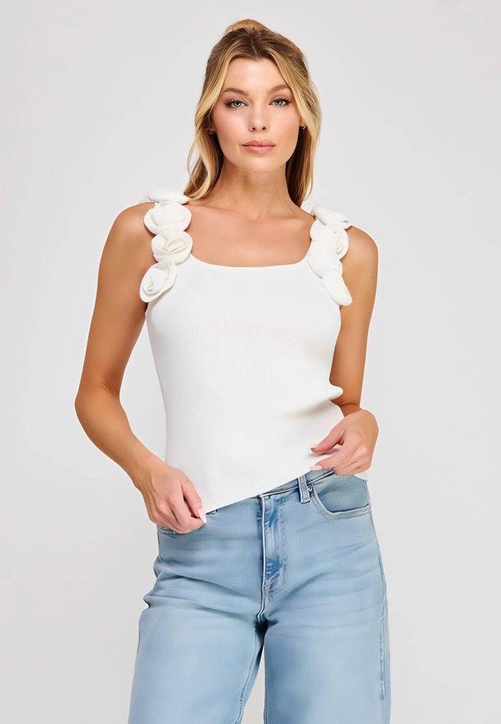 Woman wearing a white top with ruffled shoulders and light blue jeans on a plain background
