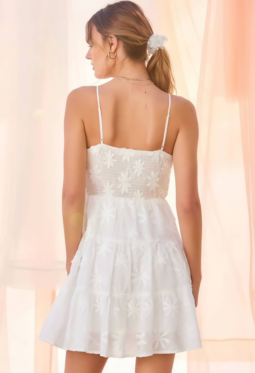 Woman wearing a white lace dress against a soft pink background