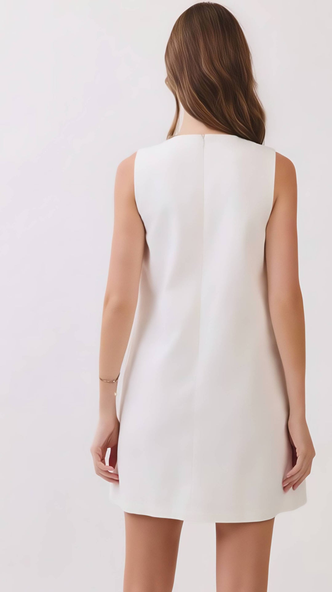 Woman wearing a white sleeveless dress against a plain background