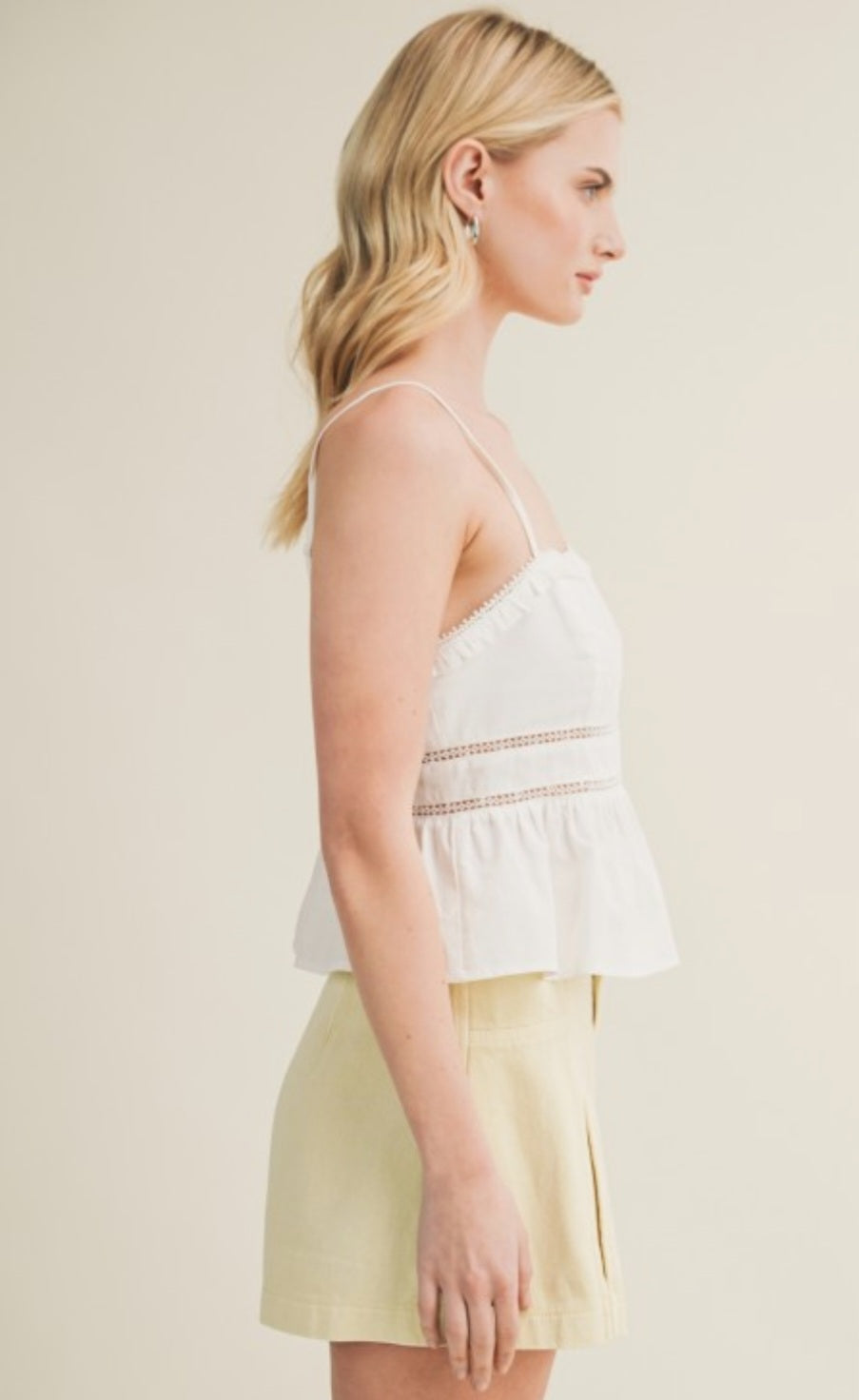 Woman wearing a white top and light yellow skirt against a plain background
