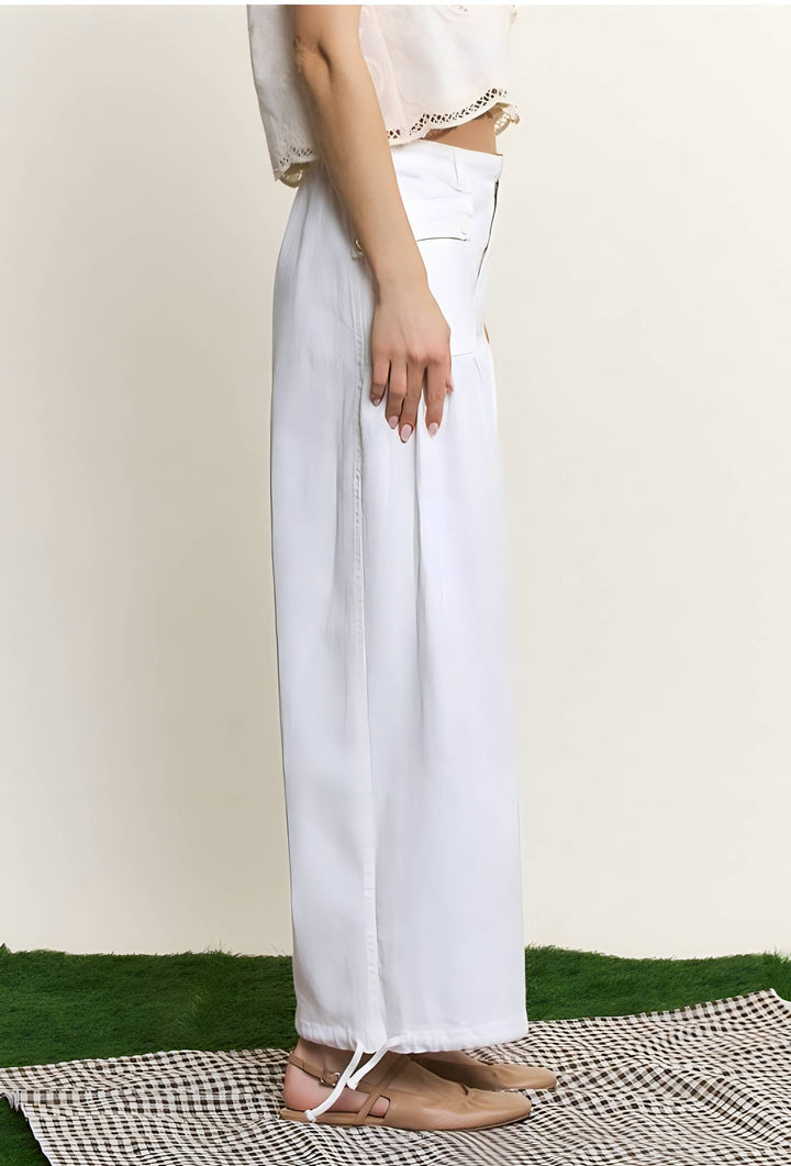 White wide-leg cropped pants with a drawstring hem, shown on a model from the waist down against a cream background.