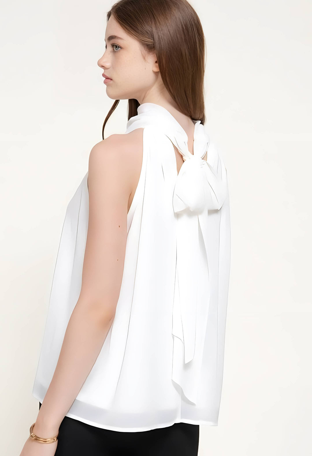 A woman shown from the back wearing a white sleeveless blouse with a large bow detail at the back neckline, paired with black bottoms, against a plain light background.