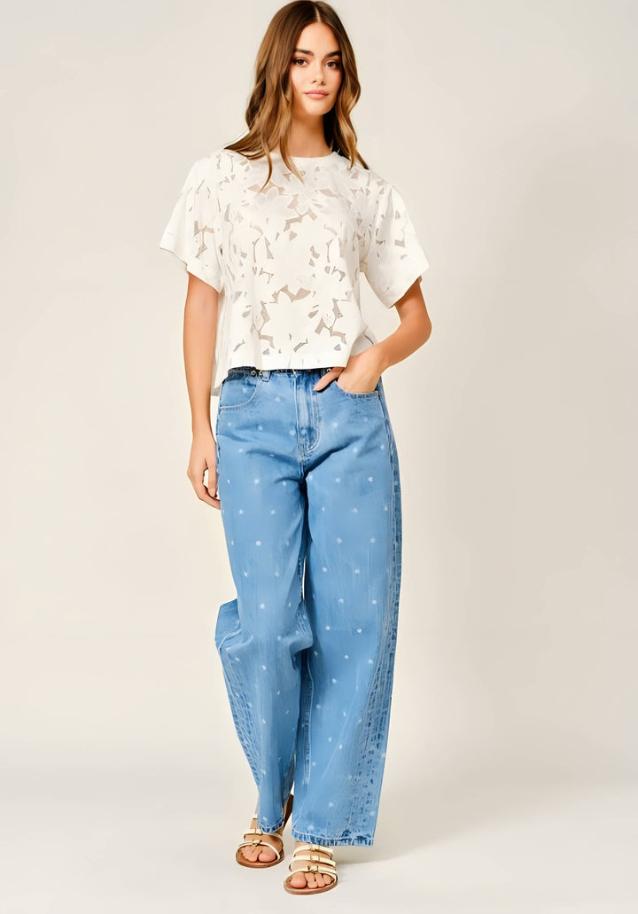 Woman wearing a white floral lace tee with jeans on a white background