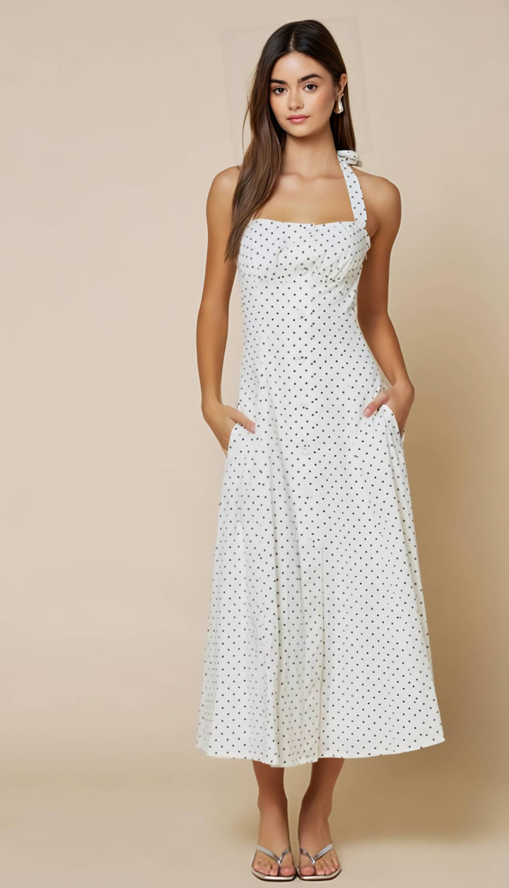 Woman wearing a white polka dot dress against a beige background