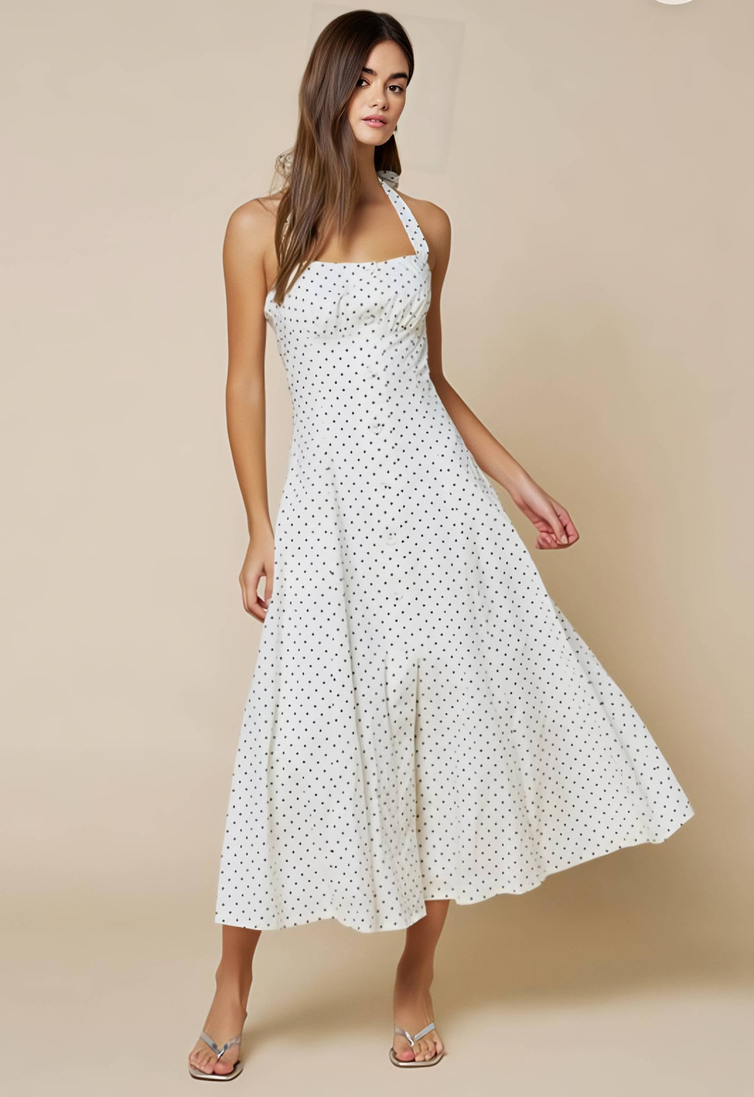 Woman wearing a white polka dot dress against a beige background