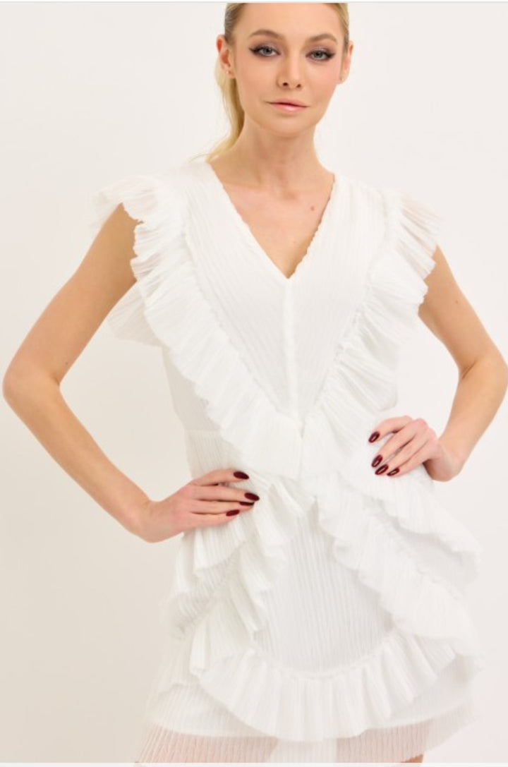 Woman wearing a white dress with ruffled details on a plain background