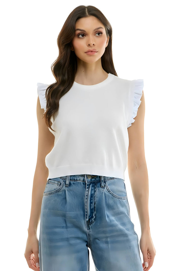 A woman modeling a white sleeveless knit top with ruffled shoulder details and light blue jeans against a plain white background.