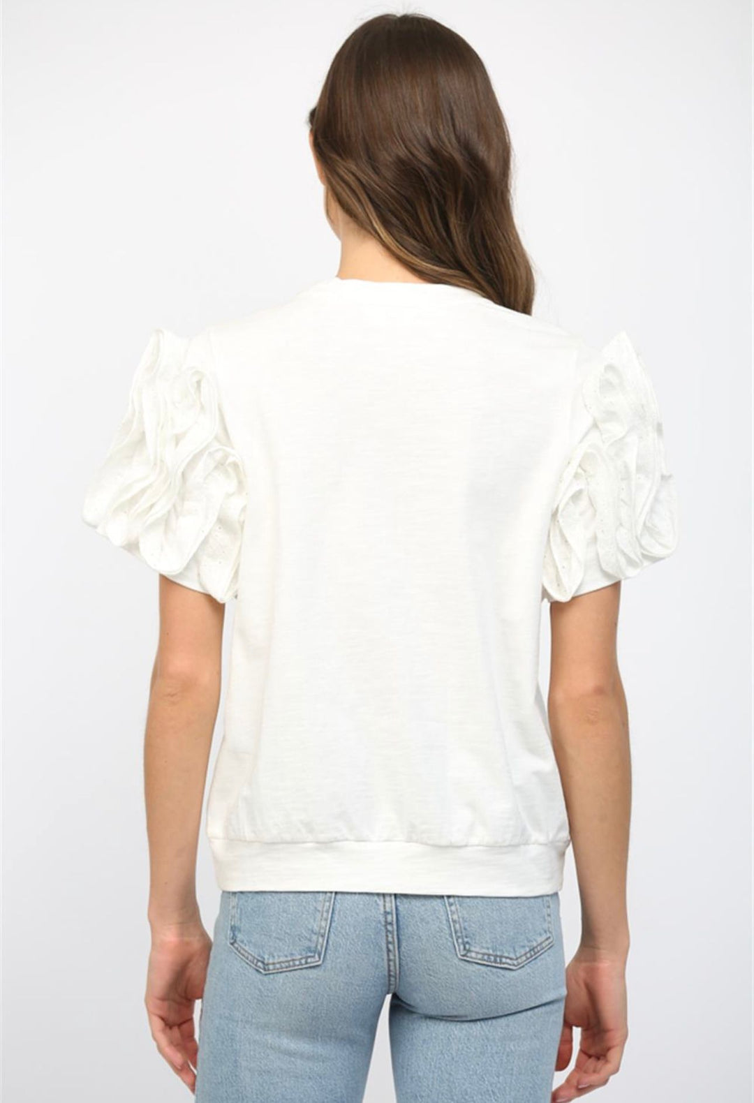 Woman wearing a white blouse with ruffled sleeves on a plain background
