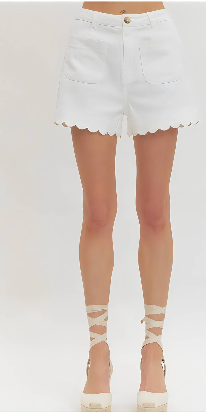 White scalloped shorts worn by a person on a plain background