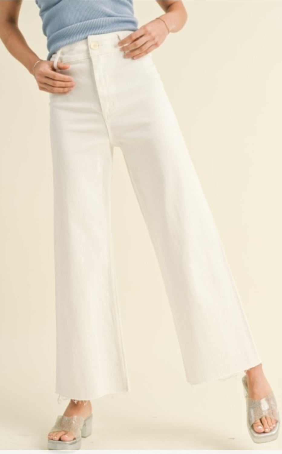 Person wearing white jeans on a beige background