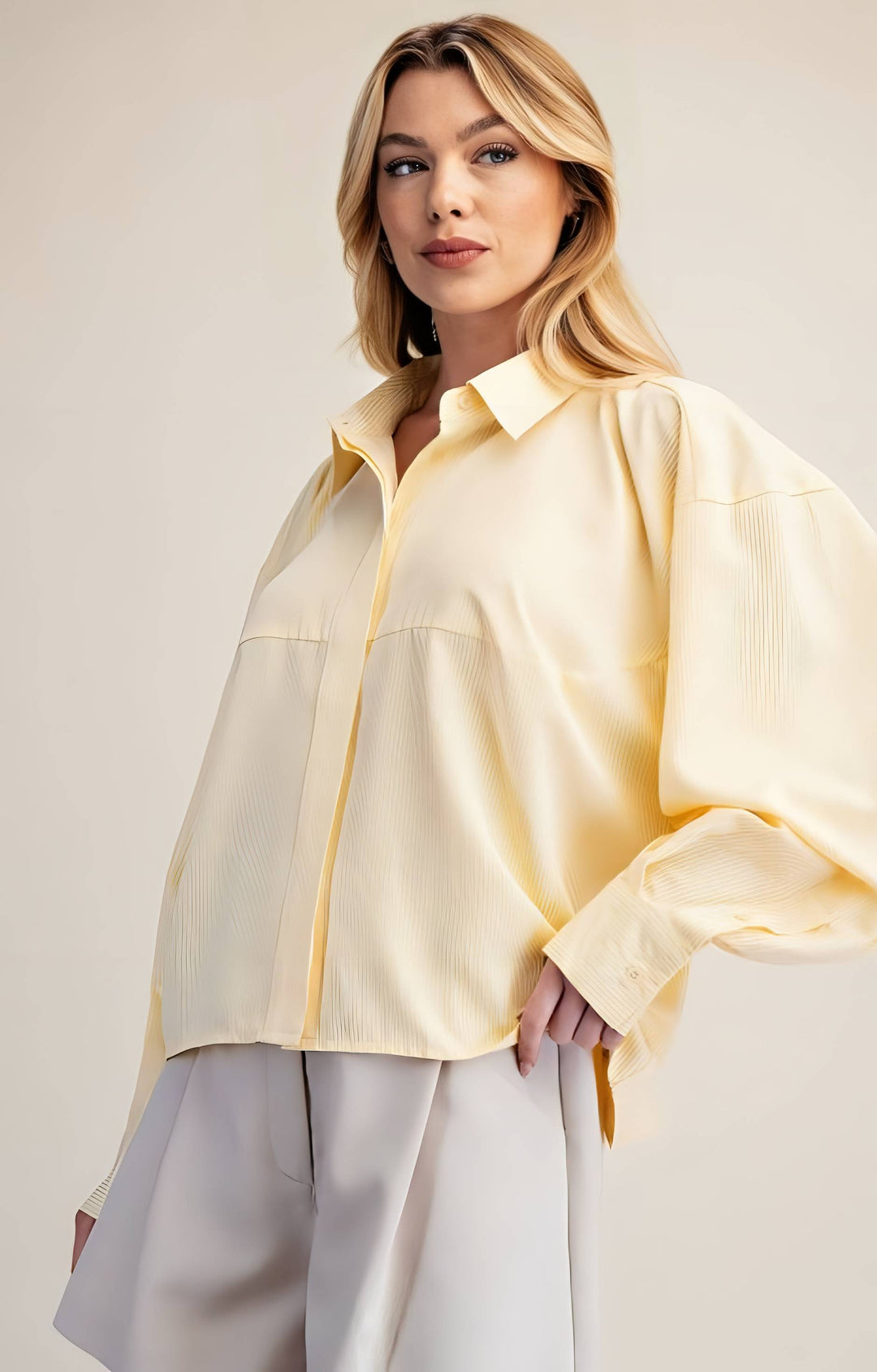 Woman wearing a light yellow blouse with a plain background