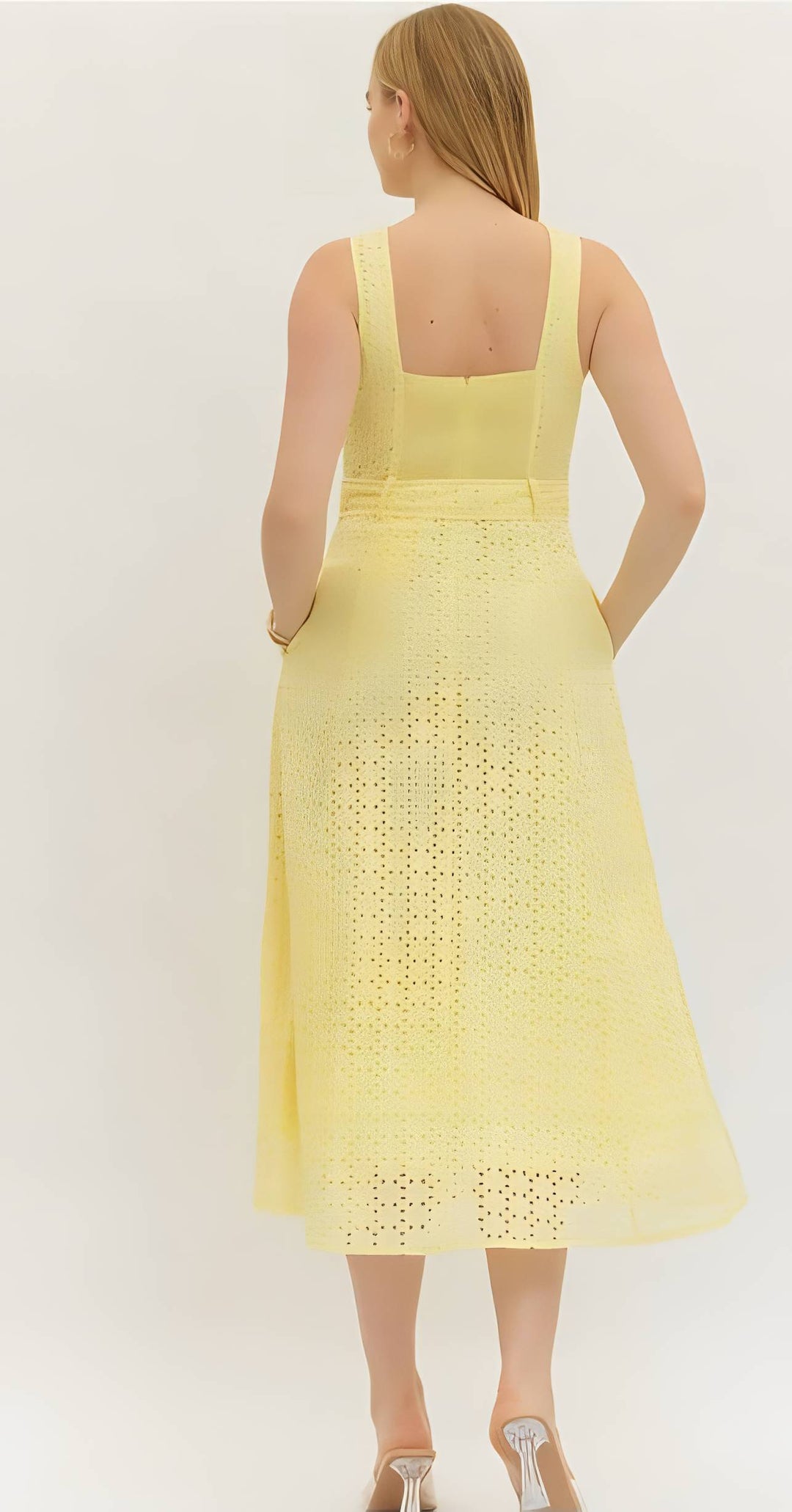 Woman wearing a yellow eyelet button belted dress on a white background