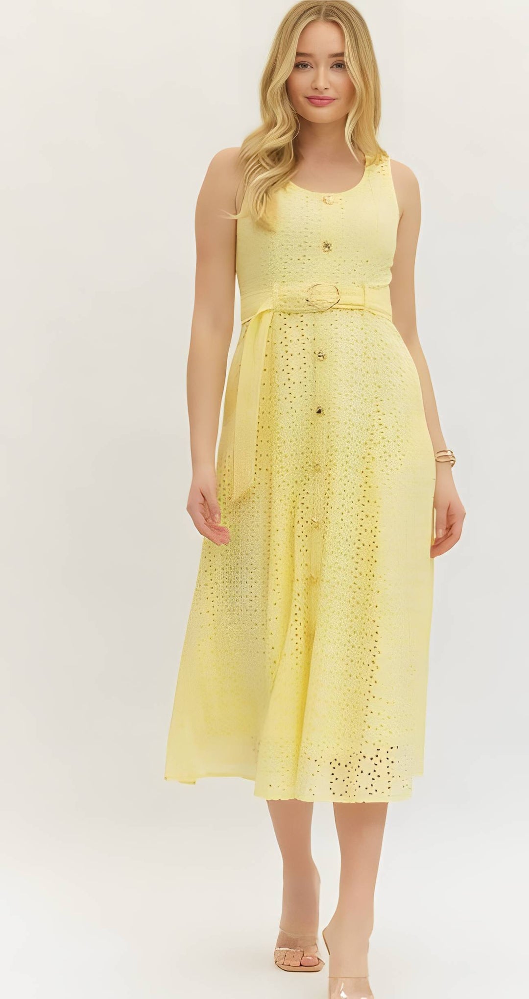 Woman wearing a yellow eyelet button belted dress on a white background