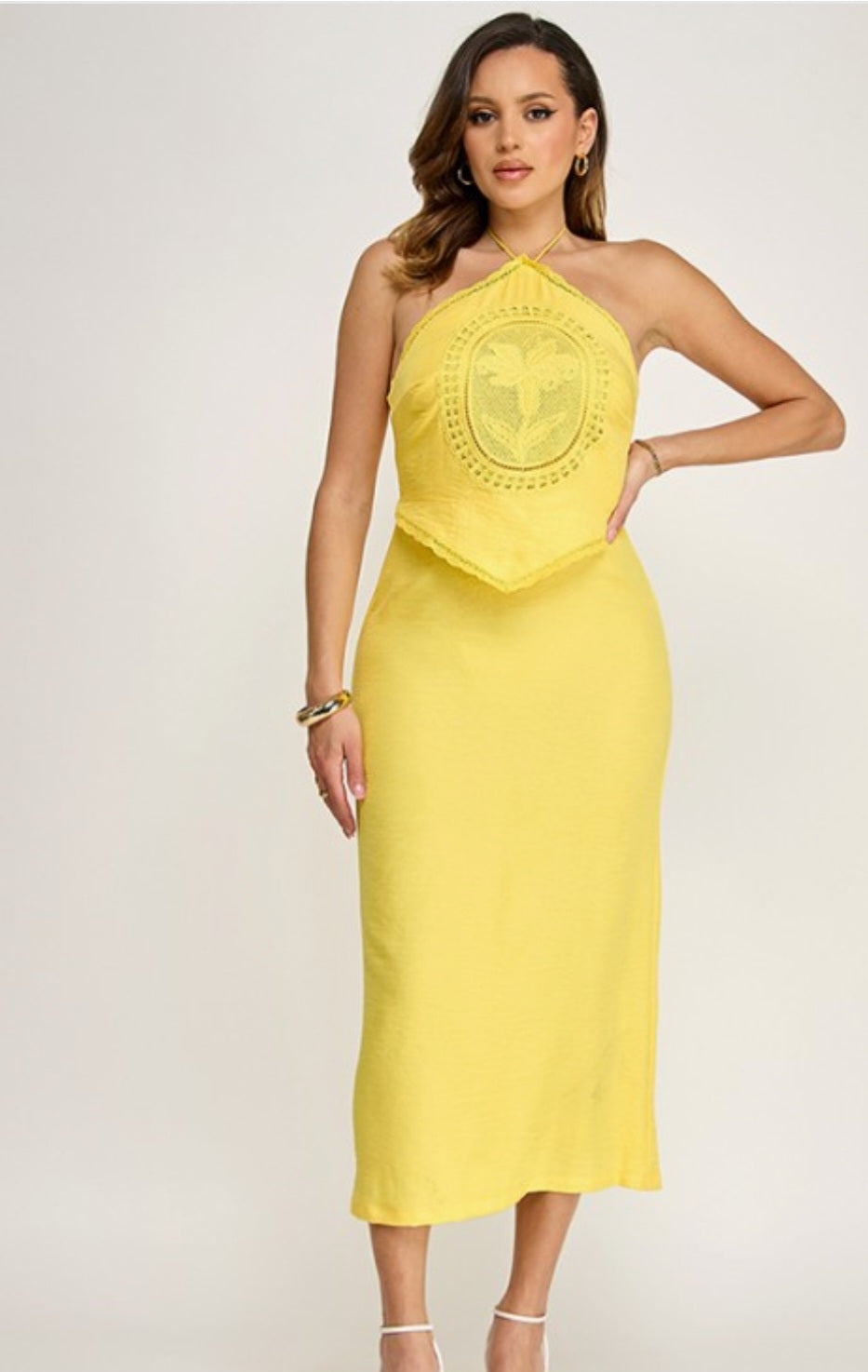 Woman wearing a yellow strapless dress with a decorative emblem on a white background