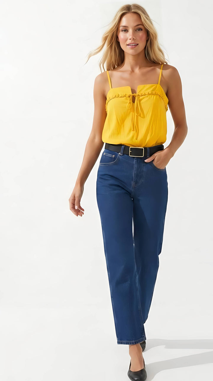 Woman wearing a yellow top and blue jeans on a white background